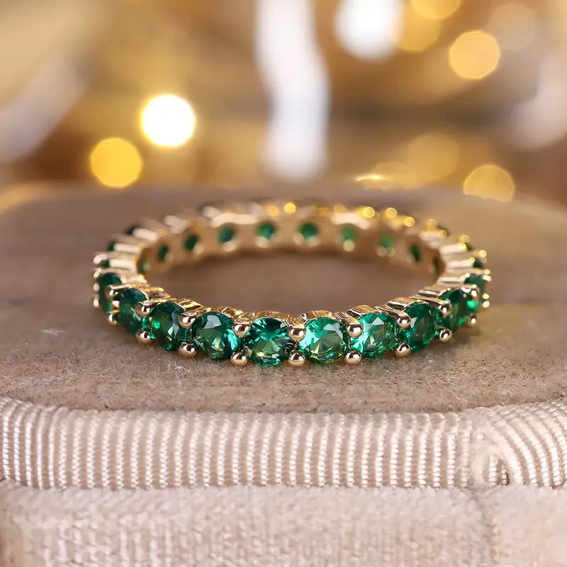 Gouden eternity ring met groene edelstenen