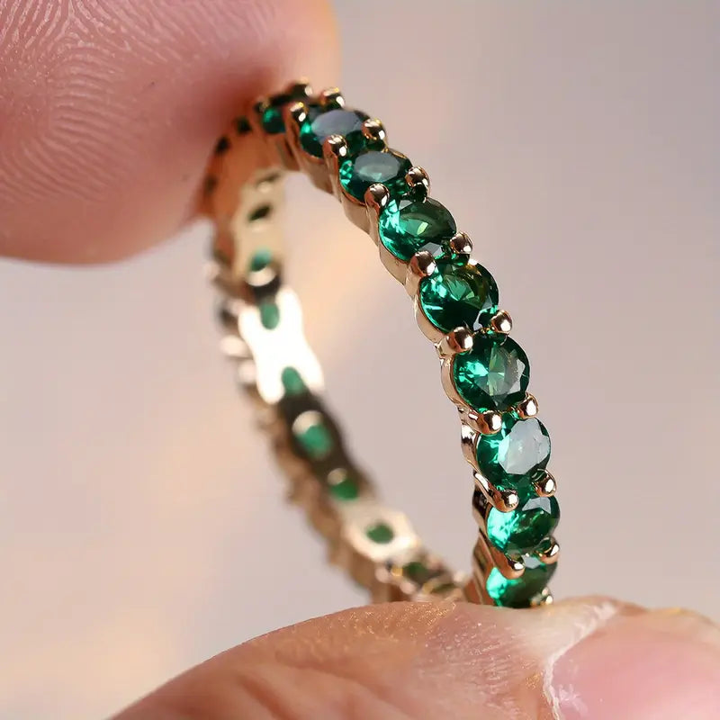 Gouden eternity ring met groene edelstenen