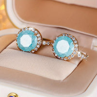 Gouden clip-oorbellen met ronde turquoise steen en zirkonia