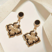 Gouden vintage oorbellen met zwart emaille klaverbloem