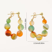 Gouden boho oorbellen met groene en oranje agaatkralen
