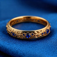 Gouden eternity-ring met blauwe stenen en bladmotief