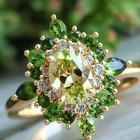 Gouden ring met groene edelstenen en halo