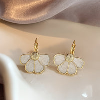 Gouden oorbellen met witte parelmoer bloem