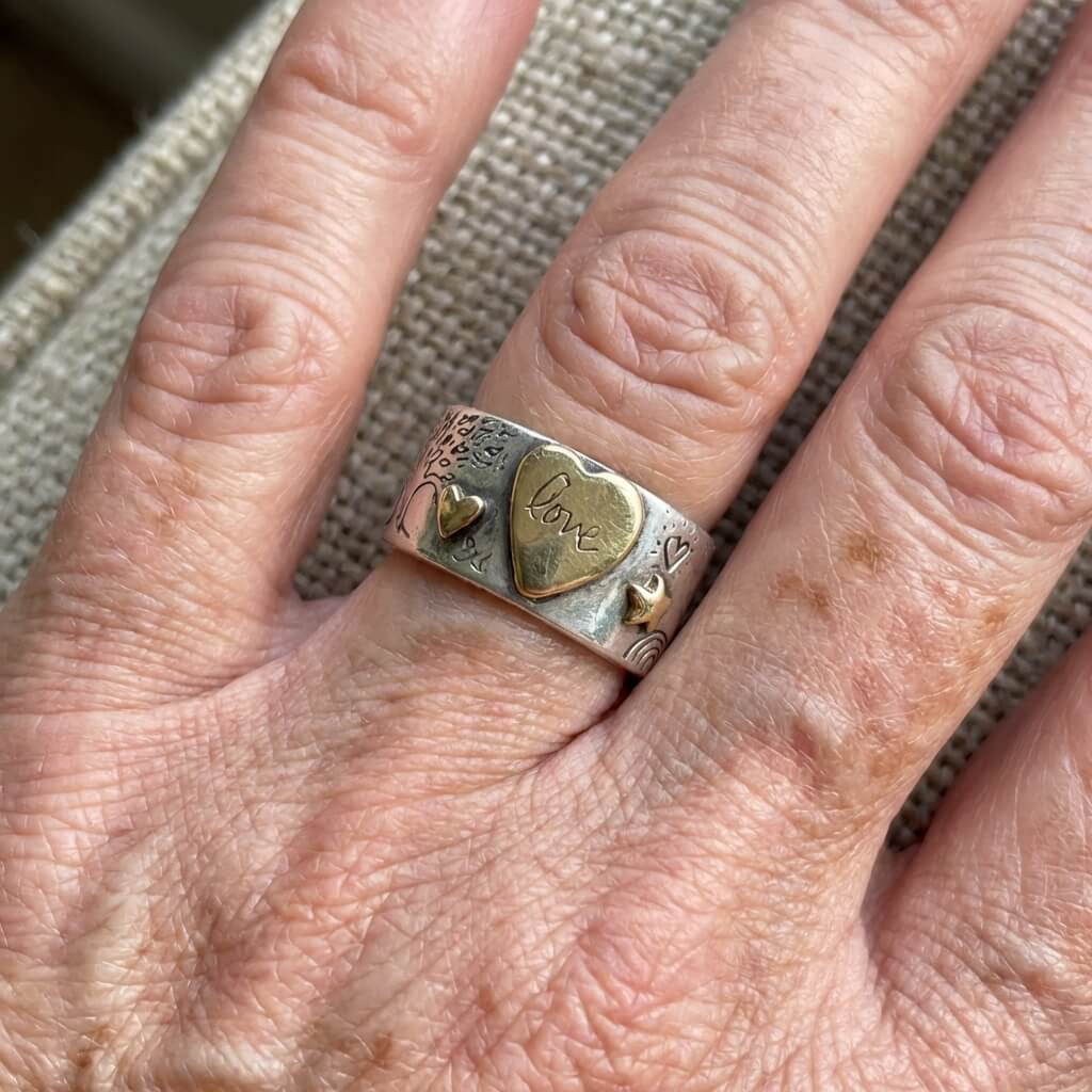 Zilveren ring met gouden hartjes en liefdesboodschap