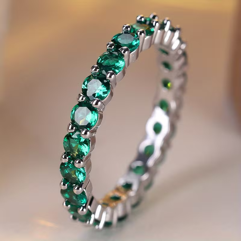 Gouden eternity-ring met groene edelstenen