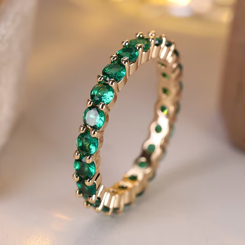 Gouden eternity-ring met groene edelstenen